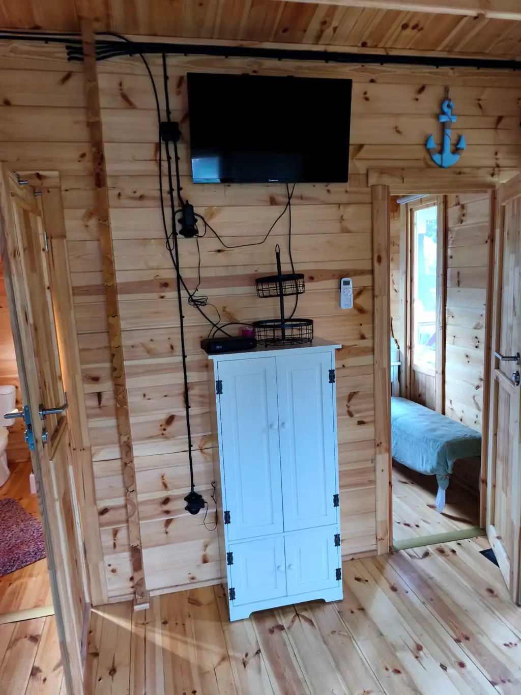 Living room wall in cottage no. 3 with a TV, a white cabinet and a decorative anchor