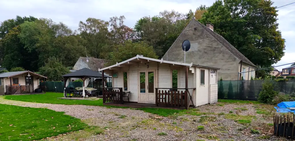 Cottage no. 3 by the lawn and gravel drive, with the garden gazebo and another Słoneczna Przystań holiday cottage in the background