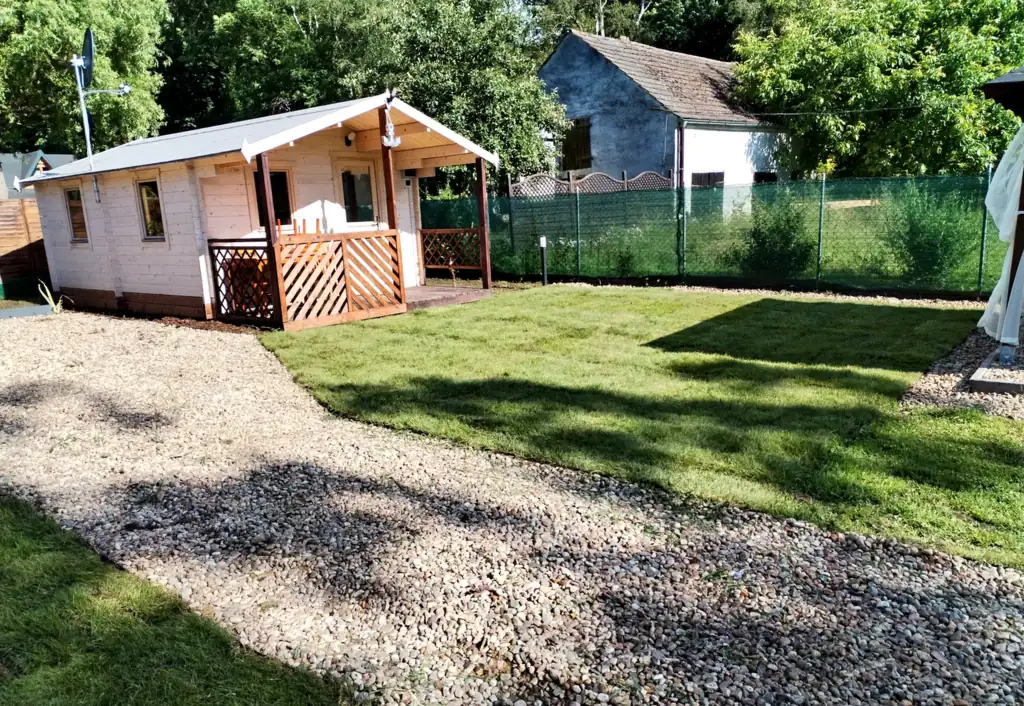 Wooden cottage by a gravel path and a well-kept lawn at Słoneczna Przystań