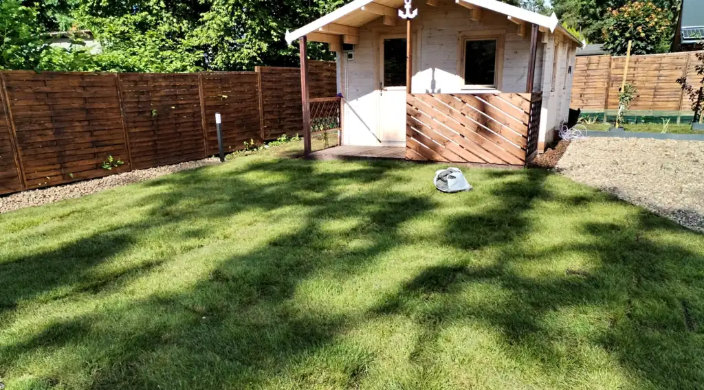Wooden holiday cottage at the end of the lawn, by the wooden fence around the property