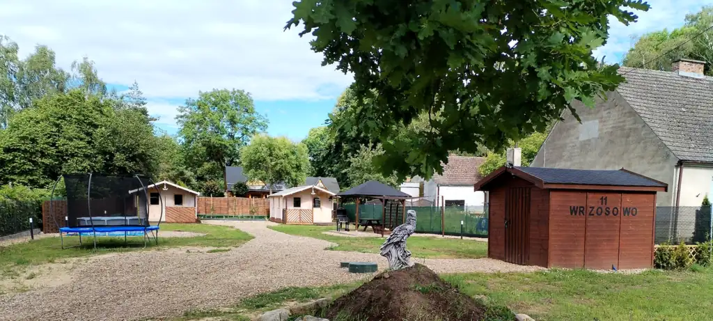 Trampolina, dwa domki i altana we Wrzosowie, po prawej budynek gospodarczy z napisem „11 Wrzosowo”, z przodu figura ptaka